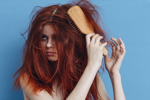 emotional woman combing her messy hair blue background. High quality photo