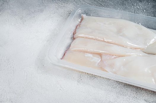 Raw squid or Calamari in a vacuum package from the supermarket. White background. Top view. Copy space.
