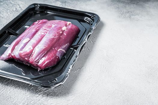 Raw lamb tenderloin in vacuum packaging. White background. Top view. Copy space.