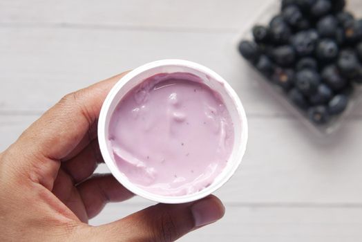 hand hold fresh yogurt in a plastic container.