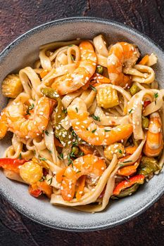 Chinese wok Stir-fry udon seafood noodles with shrimp prawns in a bowl. Black background. Top view.