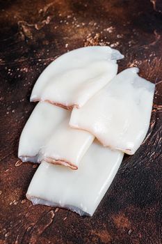 Raw Squid or Calamari tubes on a kitchen table. Dark background. Top view.