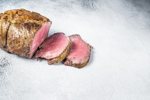 Roast beef meat fillet on kitchen table. White background. Top view. Copy space.
