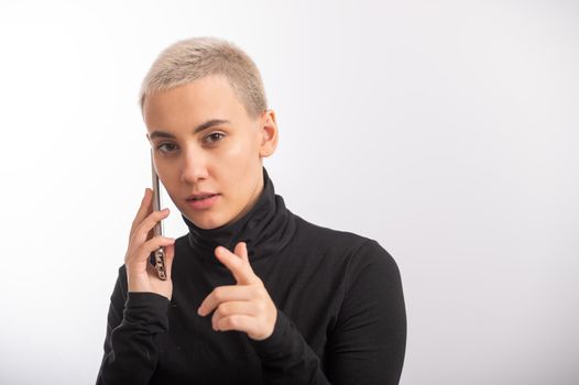 Young caucasian woman with short hair uses a smartphone on a white background