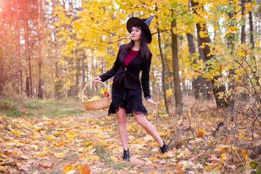 witch in the autumn forest. halloween cosplay. halloween fall holiday celebration. beautiful caucasian woman in withch costume