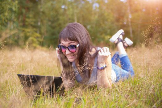 happy woman using laptop on field. happy remote work. freelancer in sunshine