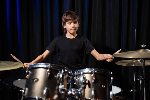 A boy plays drums in a recording studio.