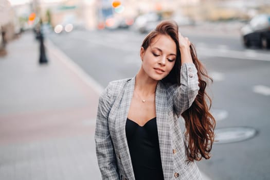 a girl in a jacket and long hair walks through the old city.A beautiful girl smiles.Girl on the road.