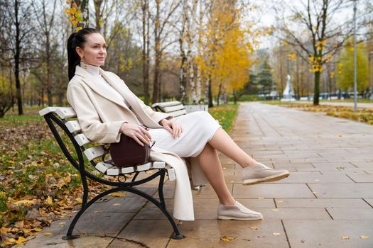 beautiful caucasian woman sitting on a bench in the park. autumn mood