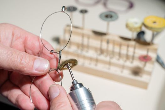 An optician technician polishes the frame of glasses. A professional optician fixes glasses