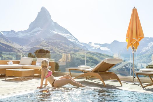 Woman enjoying the panoramic view from the pool in the alps