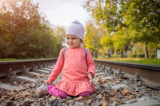 little girl sitting on the railroad tracks. toddler plays on railroad in forest