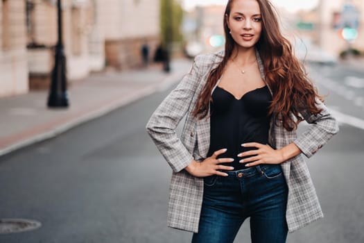 a girl in a jacket and long hair walks through the old city.A beautiful girl smiles.Girl on the road.