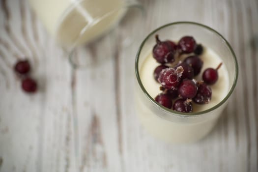 Homemade sweet yogurt with frozen berries in a glass on the table