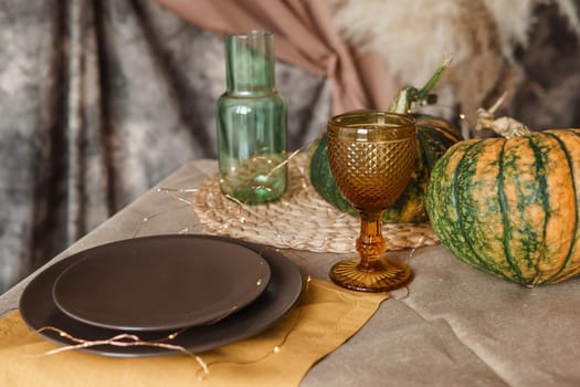 Autumn interior: a table covered with dishes, pumpkins, a relaxed composition of Japanese pampas grass. Interior in the photo Studio. Close - up of a decorated autumn table.