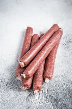 Raw butchers sausages in skins with herbs on kitchen table. White background. Top view.
