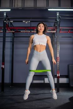 Asian woman doing exercise with fitness rubber band in the gym.