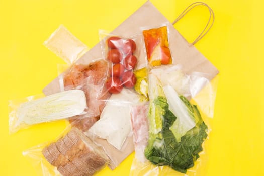 Salad dinner set: chicken, lettuce, tomatoes, peking cabbage, cheese, bacon, bread, olive oil sauces and spices. A set for delivering food for dinner on a yellow background. I cook at home. Preparing Caesar salad.