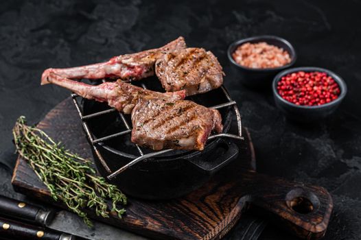 Grilled lamb mutton meat chops steaks on a grill. Black background. Top view.