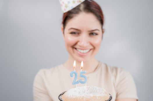 The happy woman makes a wish and blows out the candles on the 25th birthday cake. Girl celebrating birthday