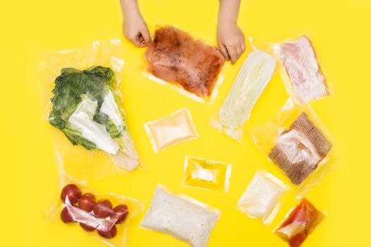 Hands holding bags of food. Salad dinner set: chicken, lettuce, tomatoes, peking cabbage, cheese, bacon, bread, olive oil sauces and spices. Set for delivering food for dinner on yellow background. I cook at home.