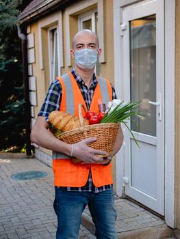 Volunteer work on food delivery during the coronavirus pandemic. Portrait of a man holding a basket of food.