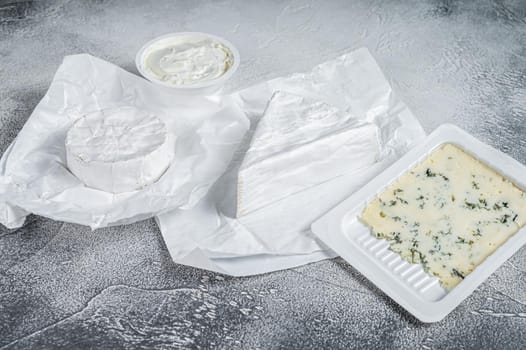 Variety of cheese kinds on kitchen table, brie, Camembert, Gorgonzola and blue creamy cheese. White background. Top view.