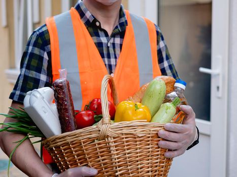 Volunteer work on food delivery during the coronavirus pandemic. Portrait of a man holding a basket of food.