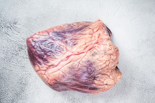 Beef or veal raw heart on a butcher table. White background. Top View.