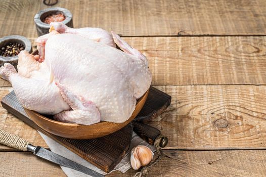 Organic chicken, raw poultry in a wooden plate. Wooden background. Top view. Copy space.