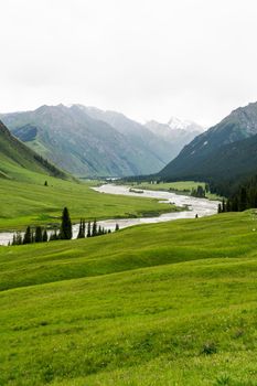 River and mountains with white clouds. Shot in Xinjiang, China.