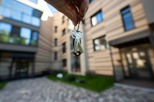 A woman holds the keys to a new house. Close-up of a female hand. Buying a property