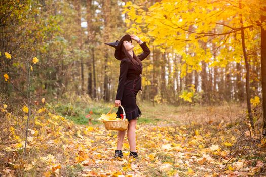 young attractive witch walks in the autumn orange forest. helloween concept