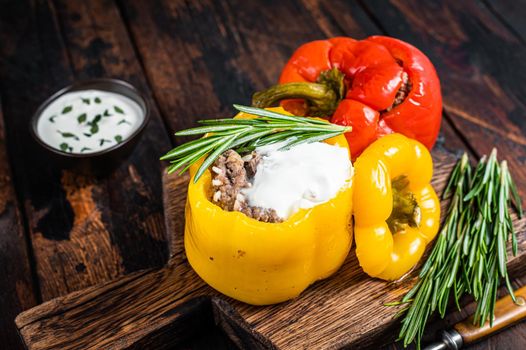 Roast bell pepper stuffed with beef meat, rice and vegetables on a wooden board. Dark wooden background. Top view.