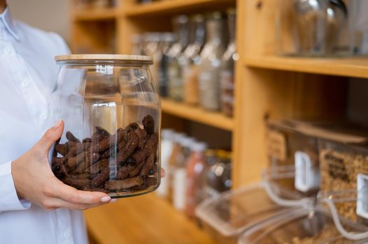 A woman holds croutons in a glass jar. Eco shop without plastic waste