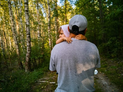 little cute toddler in dad's arms hugs his neck in the park. happy family. father's day