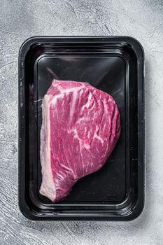 Raw cap rump steak or top sirloin beef meat steak in vacuum packaging. White background. Top view.