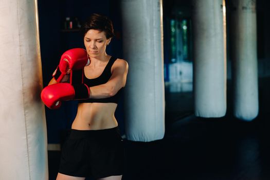 portrait of a female boxer in red gloves in the gym during training.