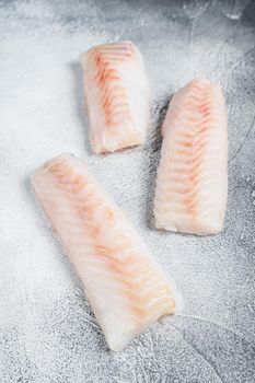 Raw Norwegian cod fish fillet on kitchen table. White background. Top view.