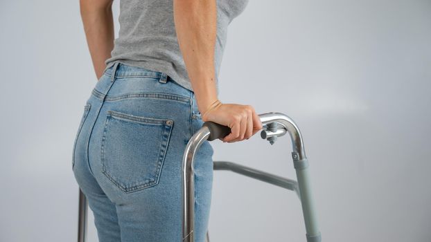 A woman is walking with a walker on a white background.