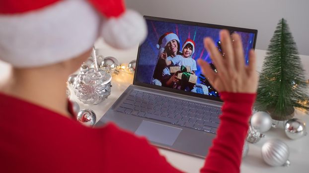 Caucasian woman calls family online on laptop and wishes a Merry Christmas. Remote meeting of the new year.