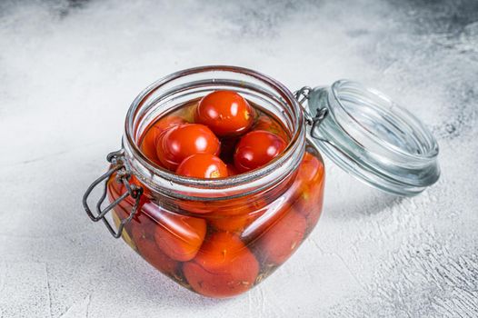 Pickled cherry tomatoes in a glass jar. White background. Top view.