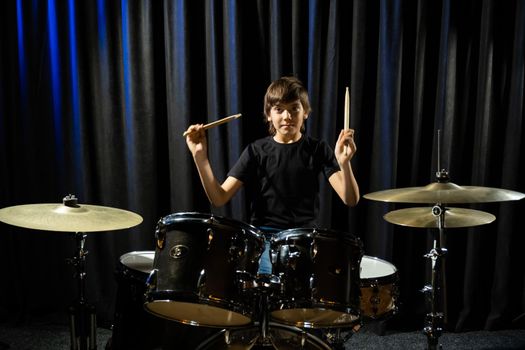 A boy plays drums in a recording studio.