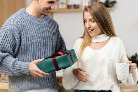 Sweet young couple opening Christmas gifts in the living room at home