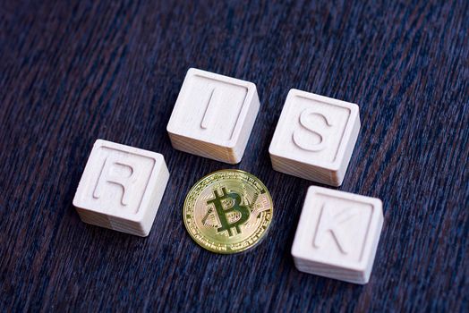 Golden bitcoin surrounded by wooden cubes forming the word risk
