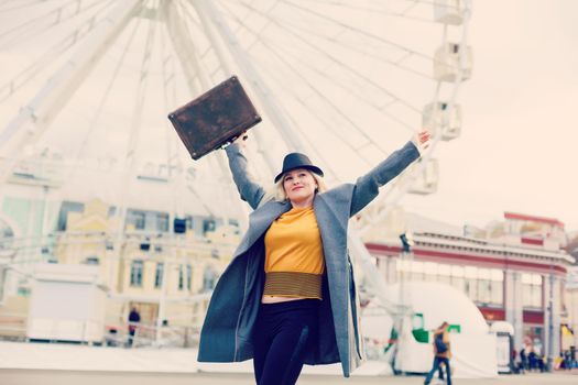 The young girl walks around the city near sights. Ferris wheel. Amusement park. autumn