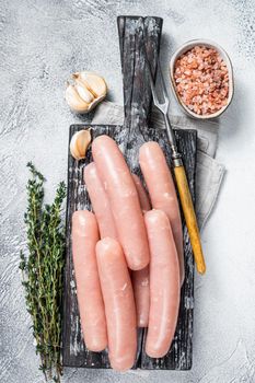 Chicken and turkey meat raw sausages on a wooden board with thyme. White background. Top view.
