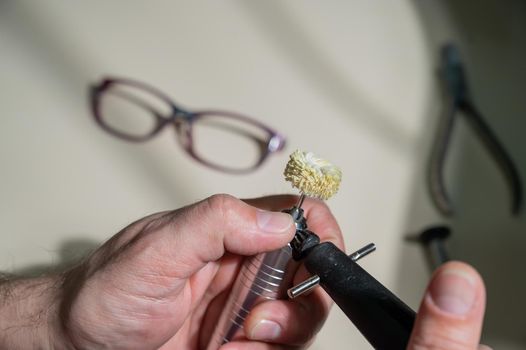 An optician technician polishes the frame of glasses. A professional optician fixes glasses