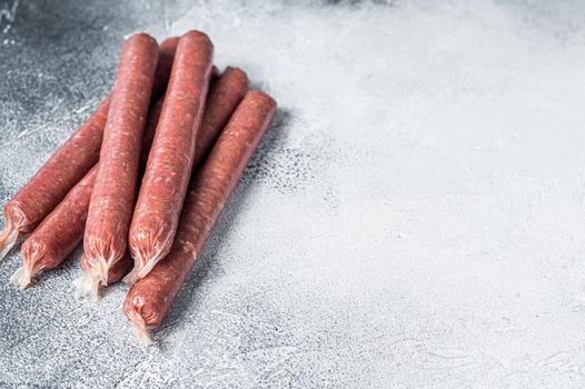 Raw butchers sausages in skins with herbs on kitchen table. White background. Top view. Copy space.