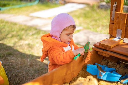 adorable toddler playing in the sandbox. cute child in fox pajamas plays in the sand. portrait of a happy baby